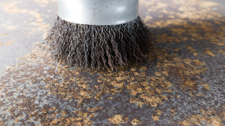 Close up of wire brush on rusty metal surface