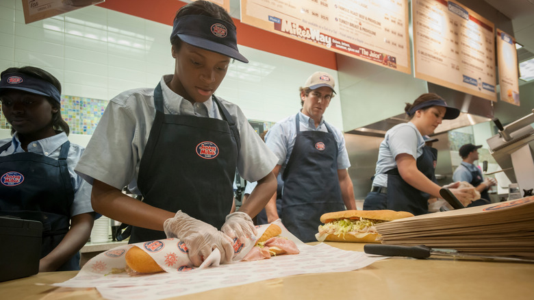 employee rolls Jersey Mike's sandwich in paper