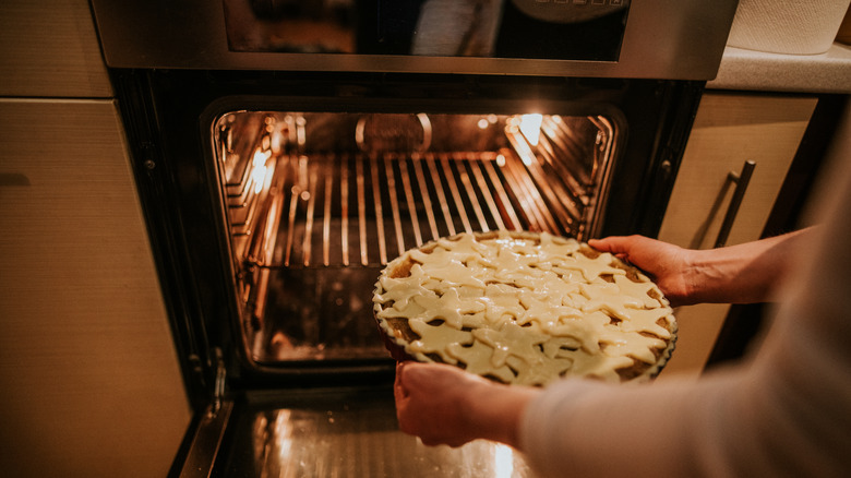 person placing pie in oven