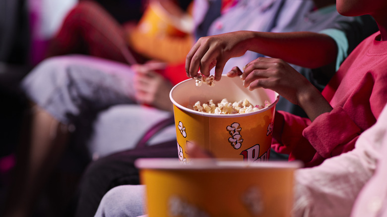 People in a movie theater with buckets of popcorn