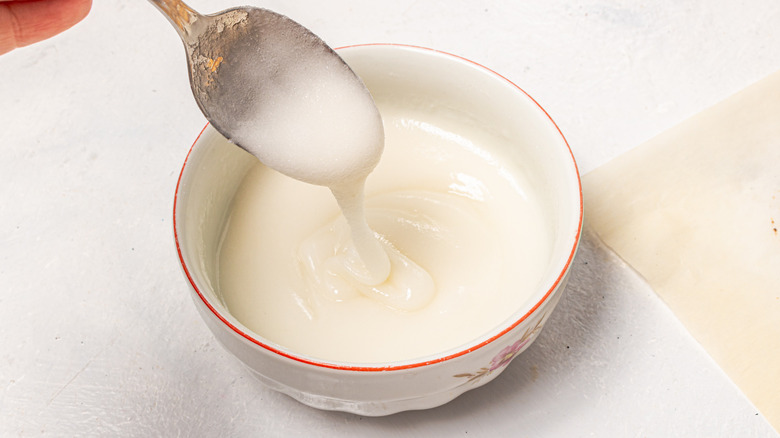 Bowl with white sugar glaze and a spoon drizzling over it