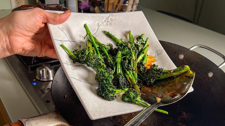 Transferring broccolini from wok to plate