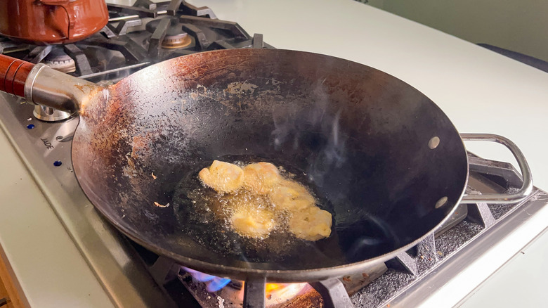 Battered shrimp cooking in hot oil in wok