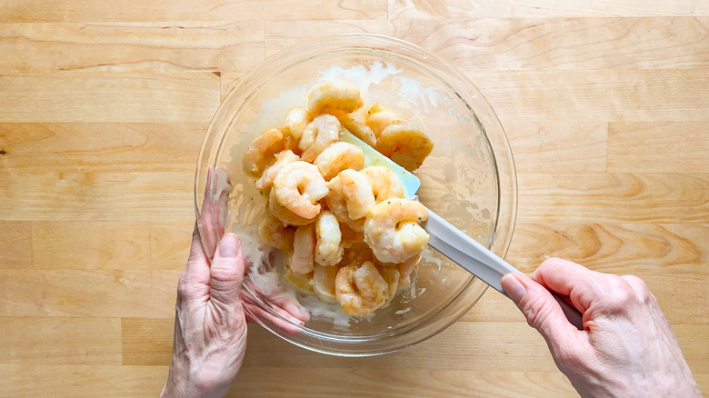 Mixing shrimp with honey mayonnaise sauce in bowl with spatula