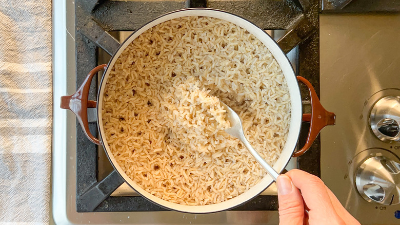 Fluffing brown basmati rice in pot with fork