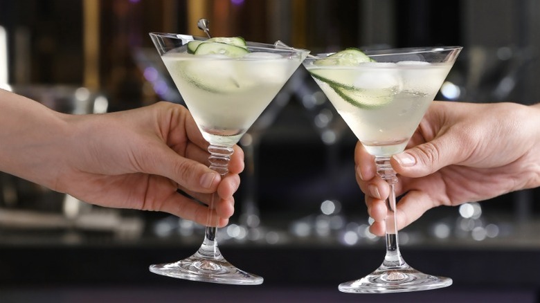 Hands clinking two martini glasses