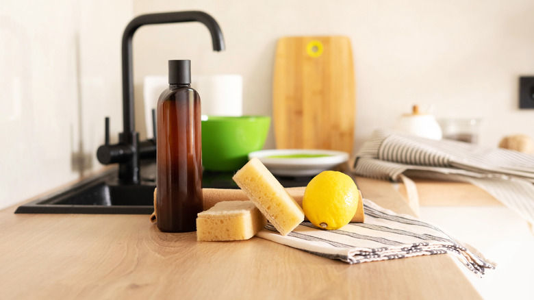 A lemon with other cleaning supplies next to a sink