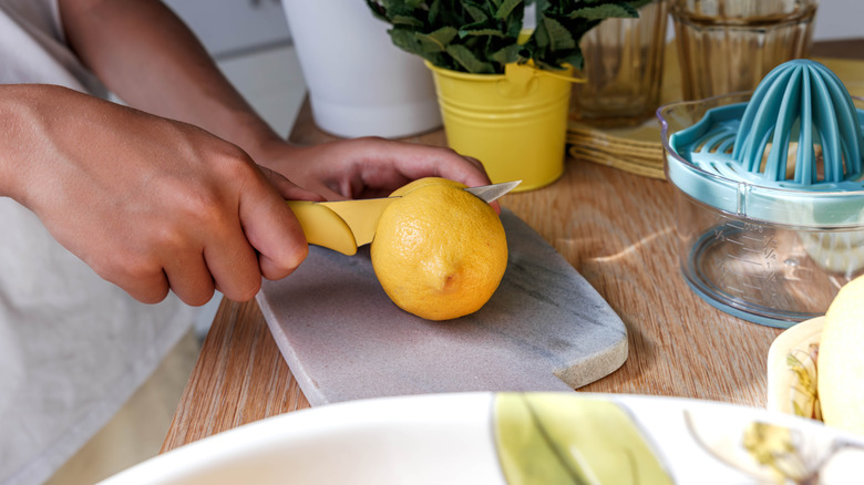 Cutting a lemon in half on cutting board