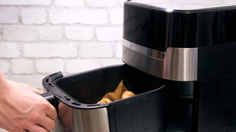 Hand removing drawer from air fryer