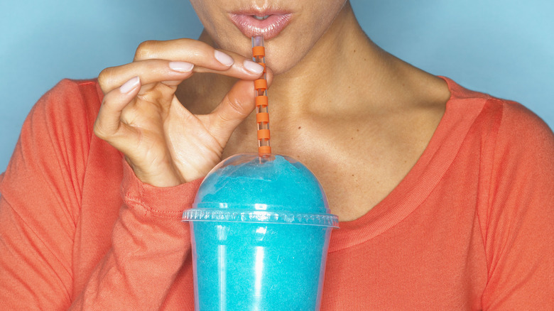 woman drinking blue slushie