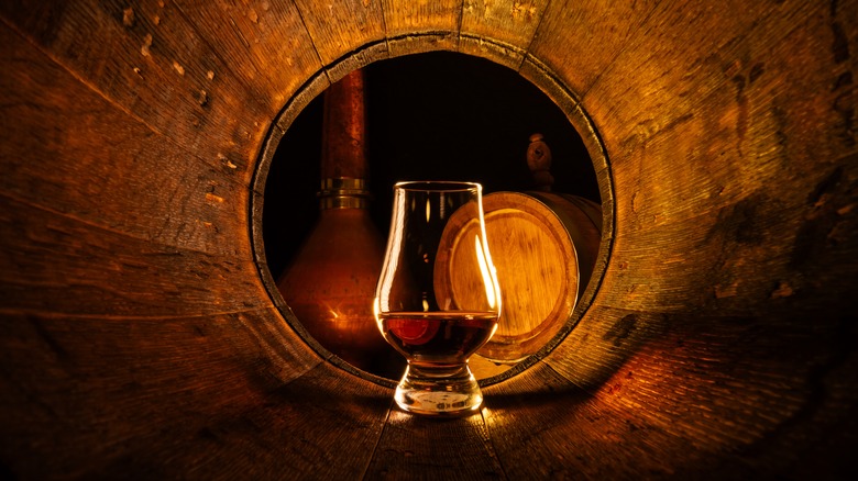 glass of bourbon in a barrel