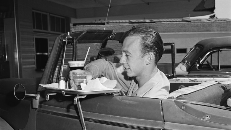 man eating fast food in his car 1950s