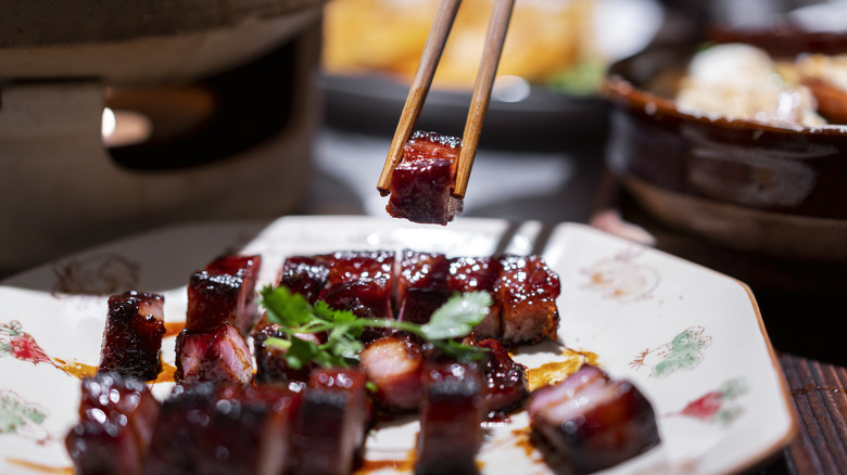 Choosing a bite of char siu with chopsticks