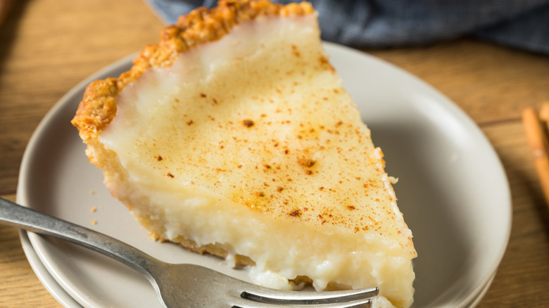 Slice of sugar cream pie on a white plate with a fork