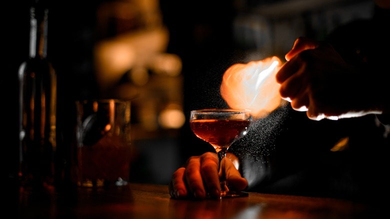 A bartender lighting alcohol vapor to make a flaming cocktail