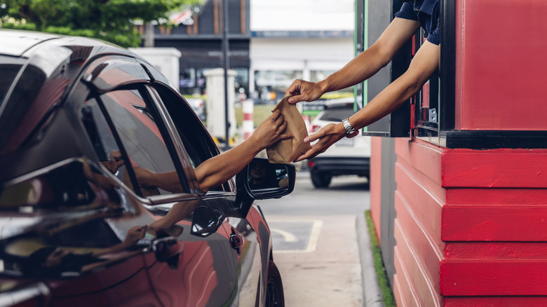 Person receiving food from a worker at a drive thru