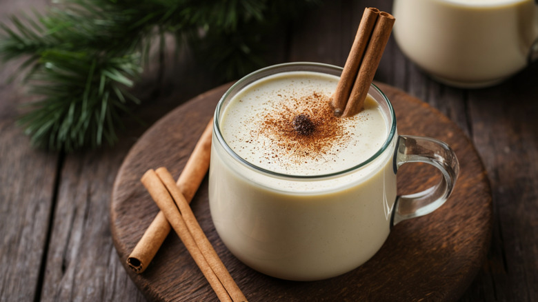 Eggnog with cinnamon sticks in a glass cup