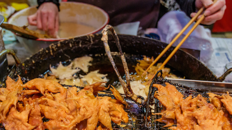 Maple leaf tempura being fried in a large pan of oil