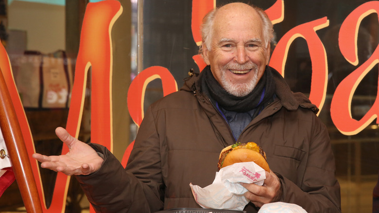 Jimmy Buffett holding a burger and smiling