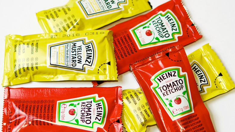 a small pile of ketchup and mustard fast food packets