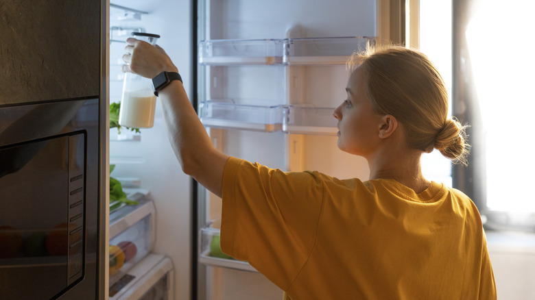 Person putting milk in fridge