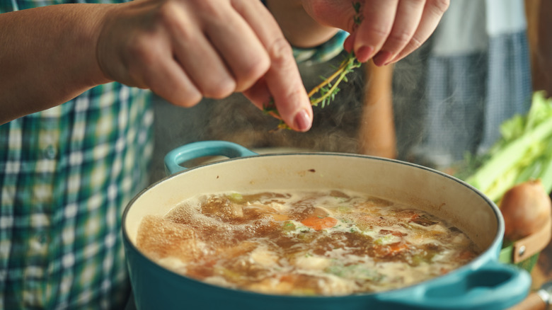 Adding fresh herbs to pot of simmering soup