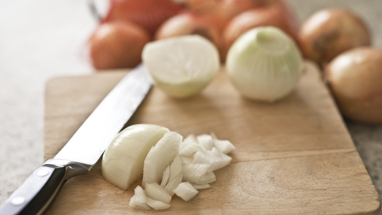 Chopped onions on a wooden cutting board with a knife