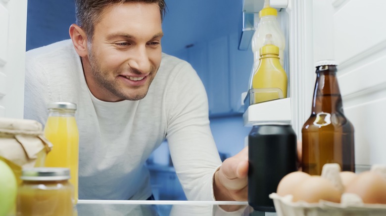 Man reaching for canned beer in the refrigerator