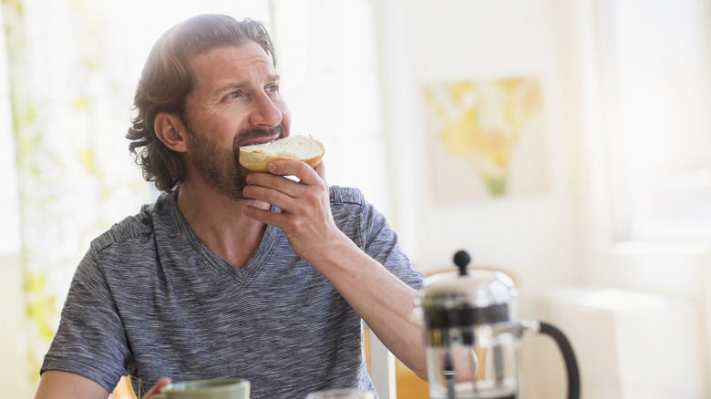 Person eating cream cheese bagel at breakfast