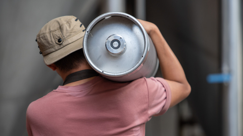 Person carrying beer keg over shoulder