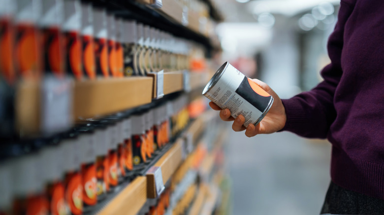 Person holding a can in a canned food aisle