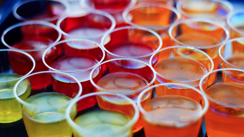 An assorted rainbow of Jell-O shots is lined up on a table.