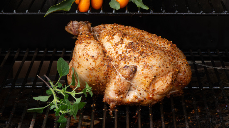 Whole chicken with bundle of herbs in a smoker