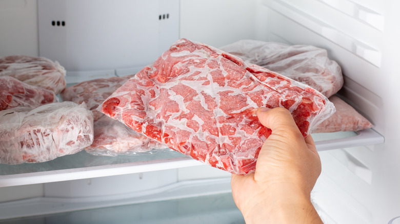 person placing frozen meat in fridge