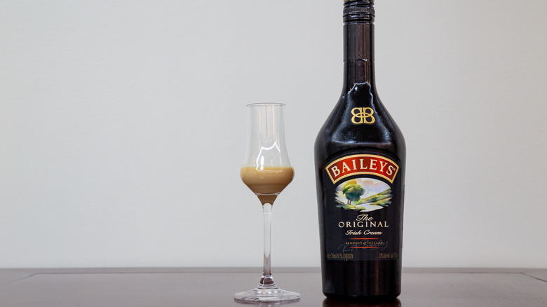 Bottle of Baileys Irish cream next to a glass of the liqueur