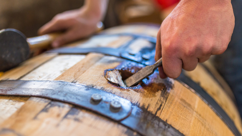 Hand opening the side of a bourbon barrel