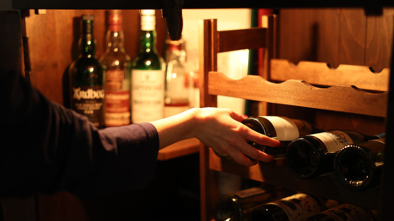 Arm grabbing a bottle out of a cellar