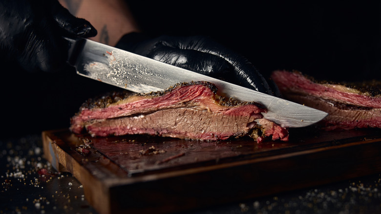 A slice of brisket as its being cut with a large knife