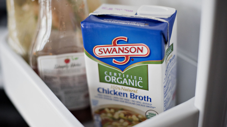 A carton of chicken broth in the refrigerator. 