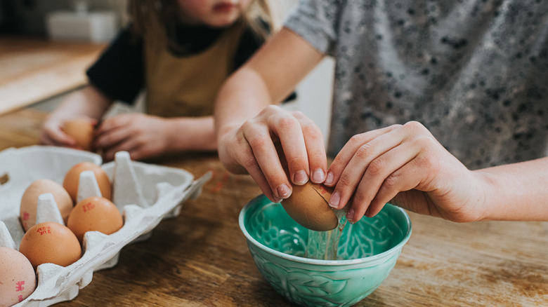 Woman and girl cracking eggs