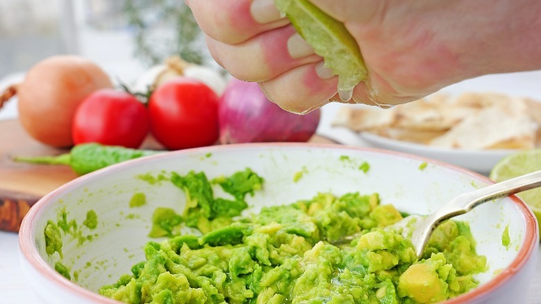 hand squeezing lime into guacamole