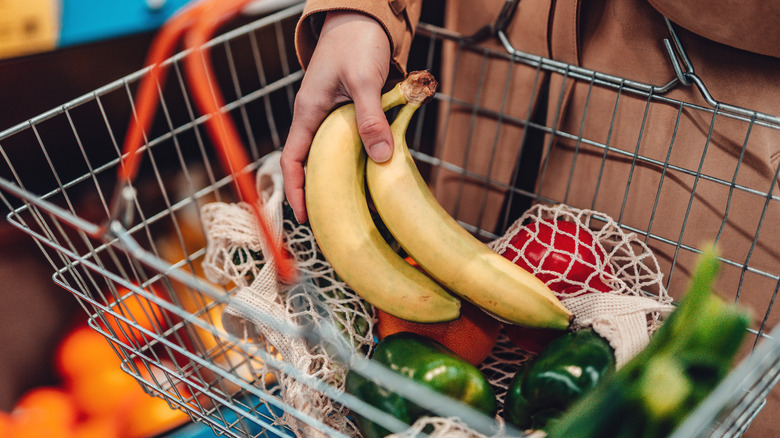 woman placing two bananas in shopping basket