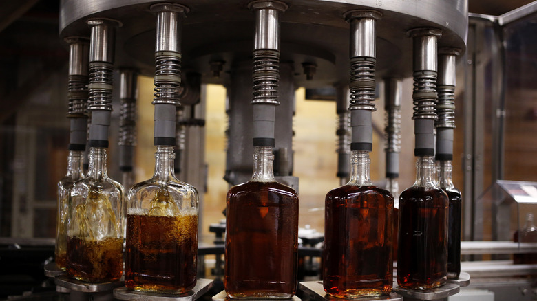 Bottles of bourbon being filled by a machine