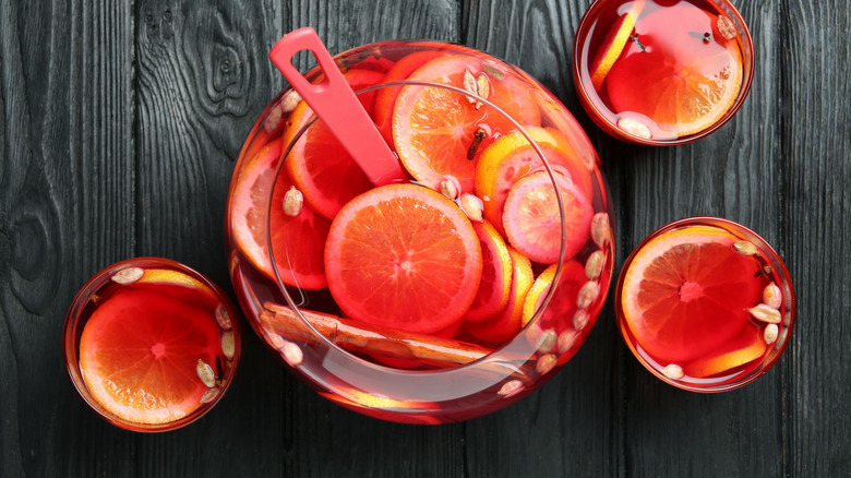 Red drink in punch bowl with citrus slices and glasses