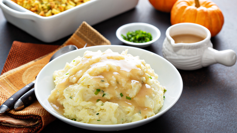 Bowl of mashed potatoes surrounded by sides.