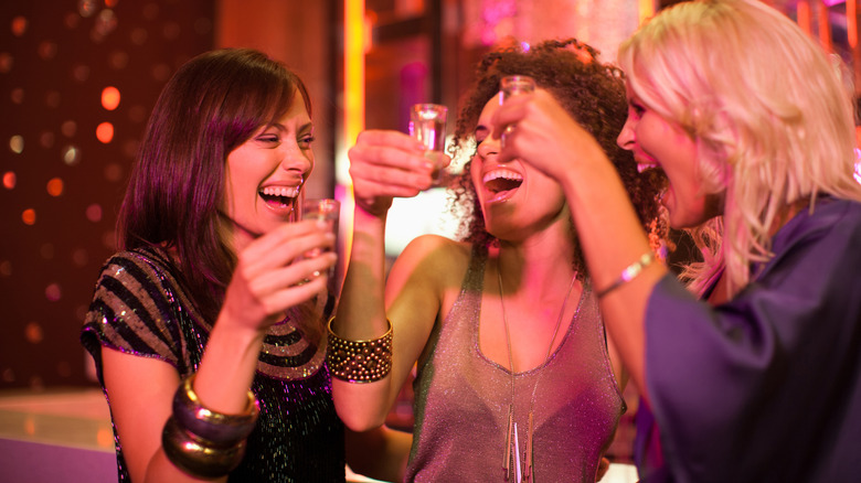 Three people laughing and celebrating with shots