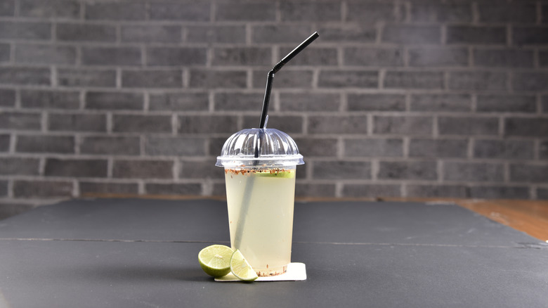 bootleg cocktail in plastic cup with straw and lime slices