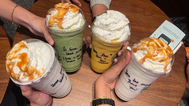 People holding four Starbucks Frappuccinos