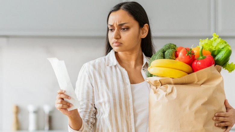 Woman checking receipt and holding grocery bag