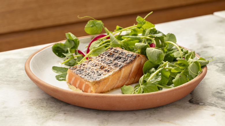 A filet of dry-aged salmon belly served with greens at Theodora in Brooklyn